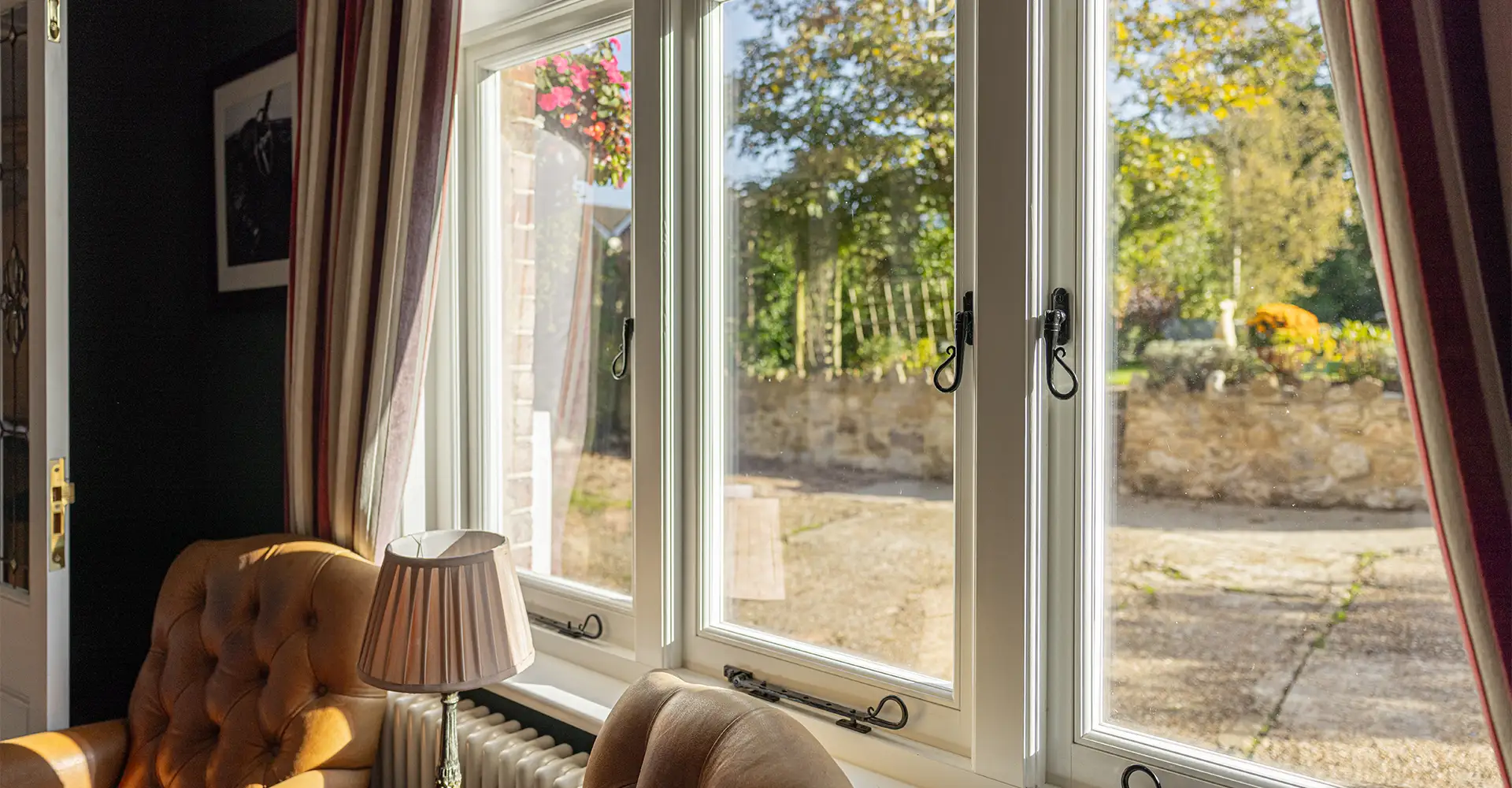 White timber stormproof windows looking out over a stone terrace and garden