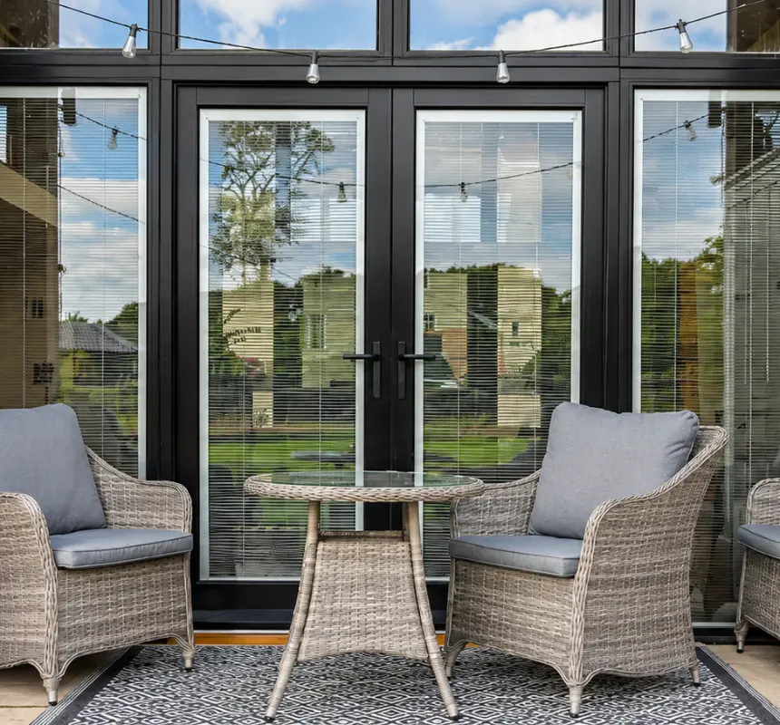 Black timber French doors onto a brick terrace at a barn conversion, made by Spittlywood