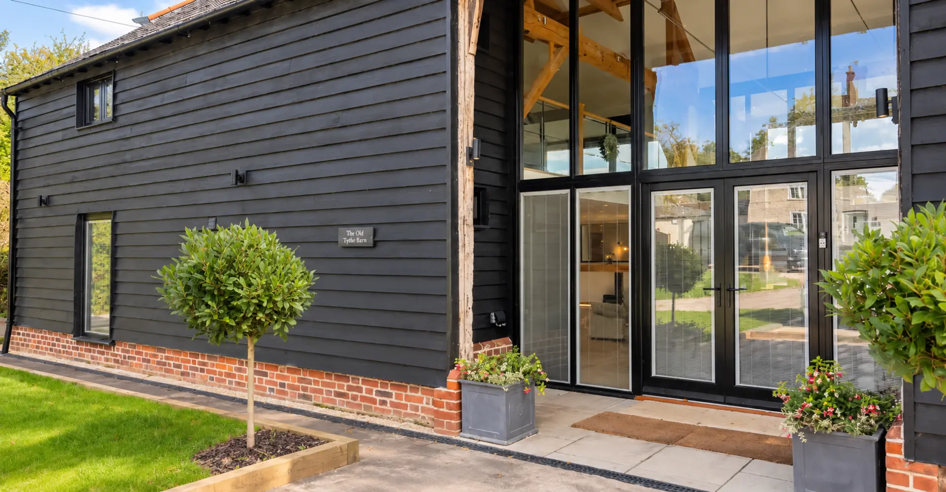 Black weatherboarded barn with full height glazed entrance doors, made by Spittlywood