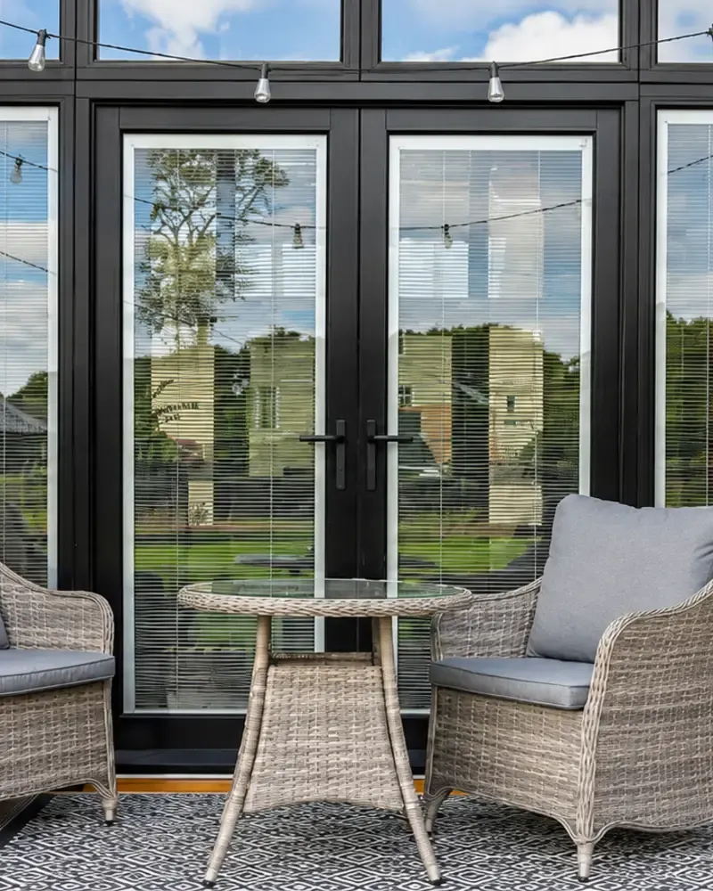 Black timber French doors onto a brick terrace at a barn conversion, made by Spittlywood
