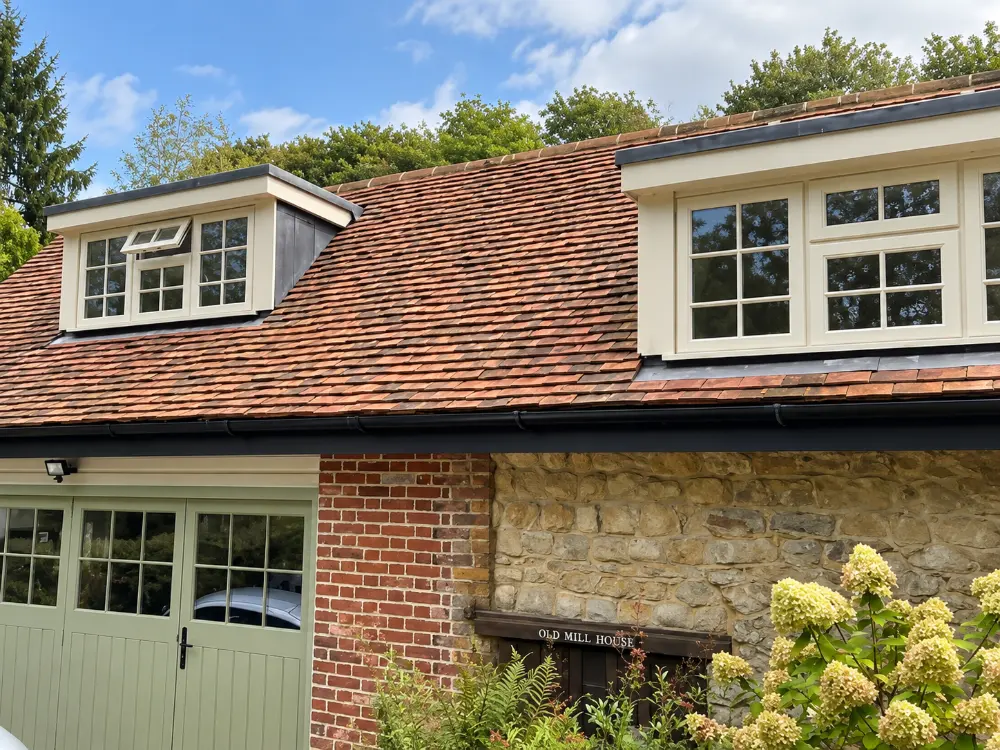 Cream timber stormproof windows in tiled dormers on a stone house, made by Spittlywood