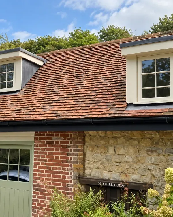 Cream timber stormproof windows in tiled dormers on a stone house, made by Spittlywood